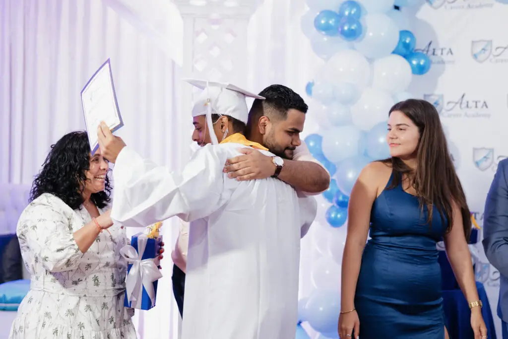 Students embracing on stage at graduation.